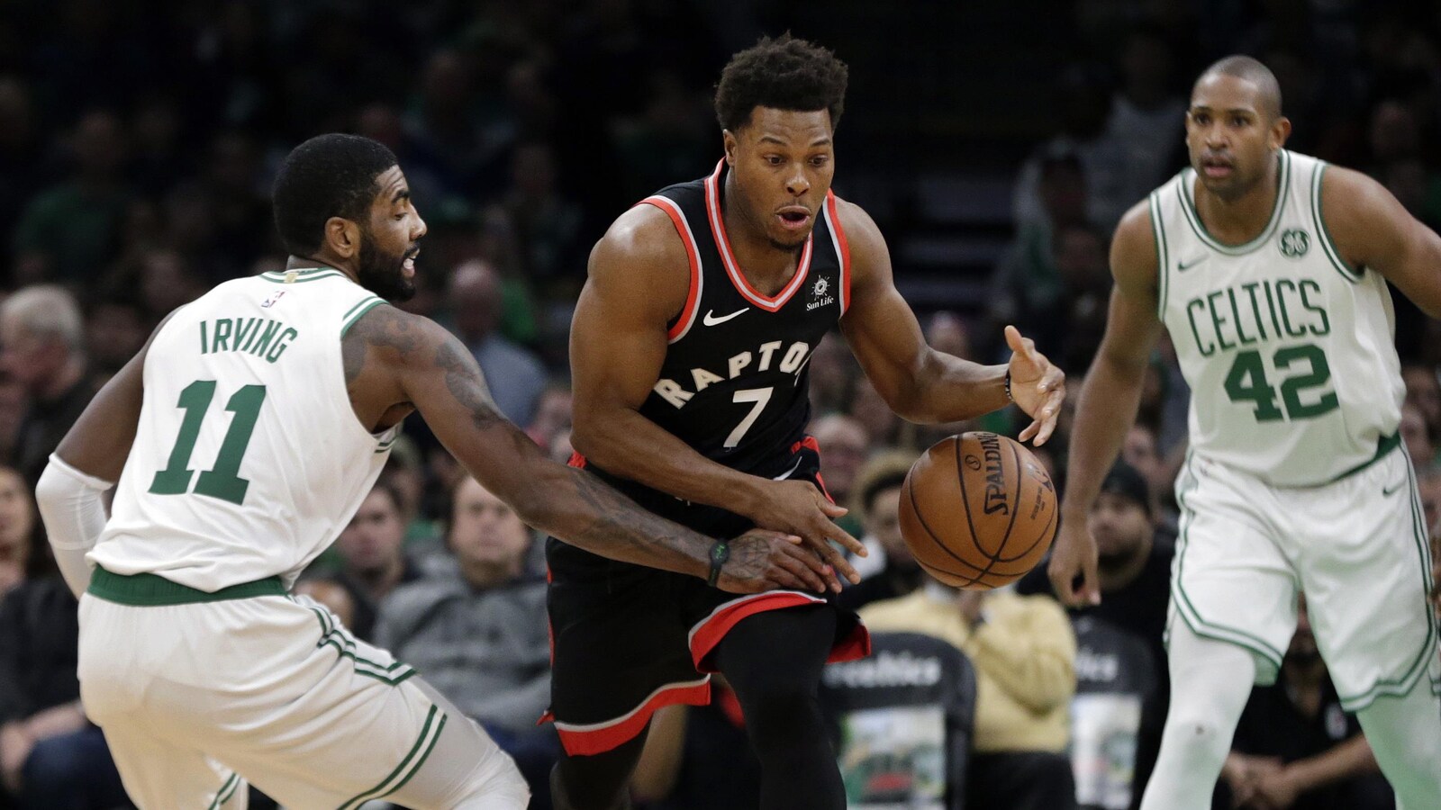 Le garde des Celtics Kyrie Irving vole le ballon à celui des Raptors Kyle Lowry, sous le regard de l'ailier fort Al Horford.