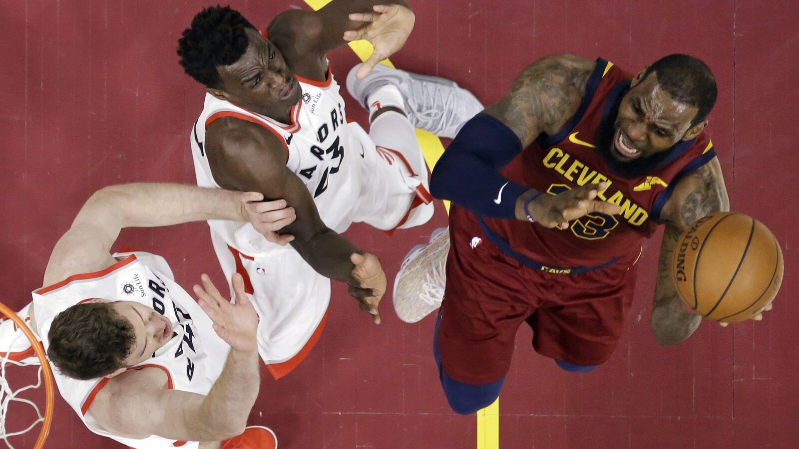 Pascal Siakam et Jakob Poeltl tentent de bloquer LeBron James.