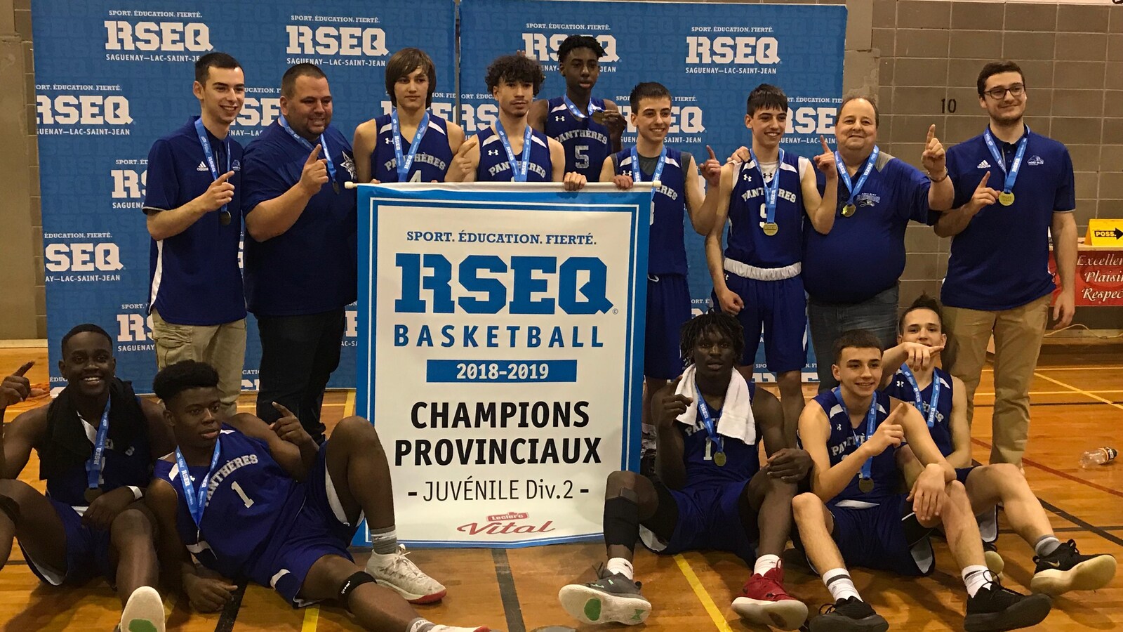 Des joueurs de basketball célèbrent une victoire avec la bannière de champion.