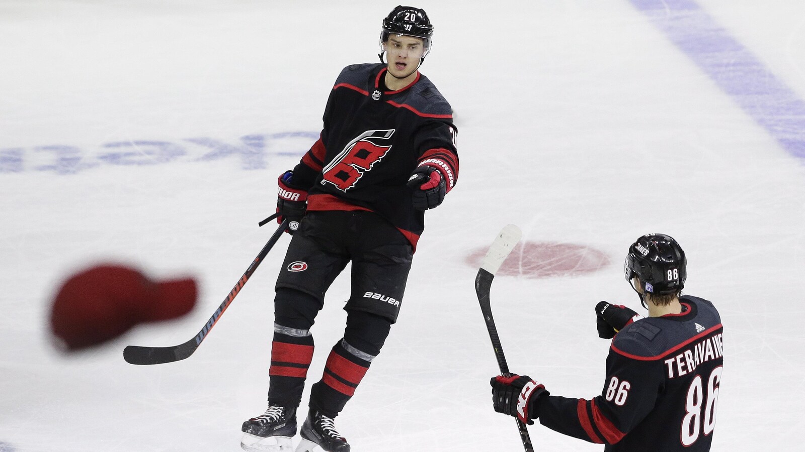 Sebastian Aho célèbre son troisième but du match avec Teuvo Teravainen, alors que la foule lance des chapeaux sur la glace.