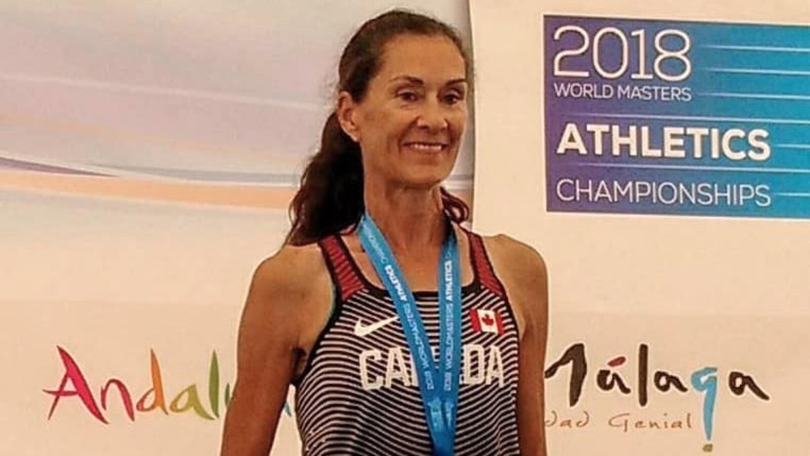 Patty Blanchard est sur le podium avec une médaille d'or au cou et un certificat attestant sa performance.