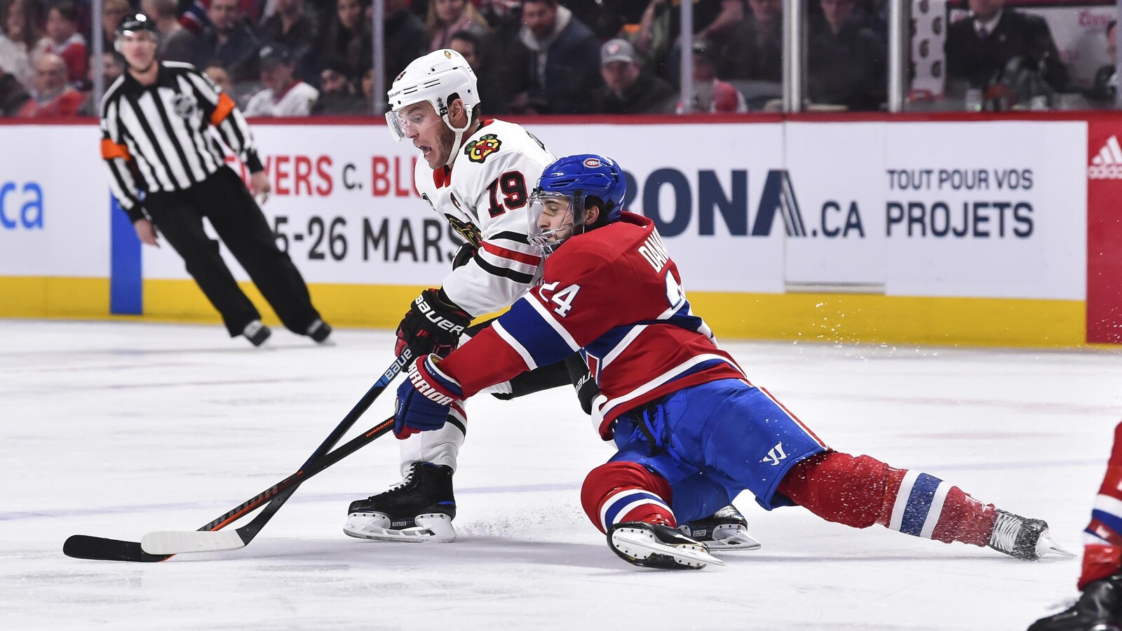 Phillip Danault (à droite) tente de soutirer la rondelle à Jonathan Toews.