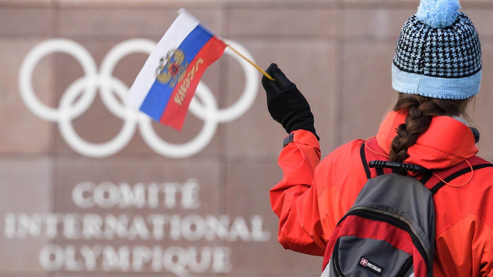 Une femme agite un drapeau de la Russie devant le quartier général du Comité international olympique, à Lausanne, en Suisse.