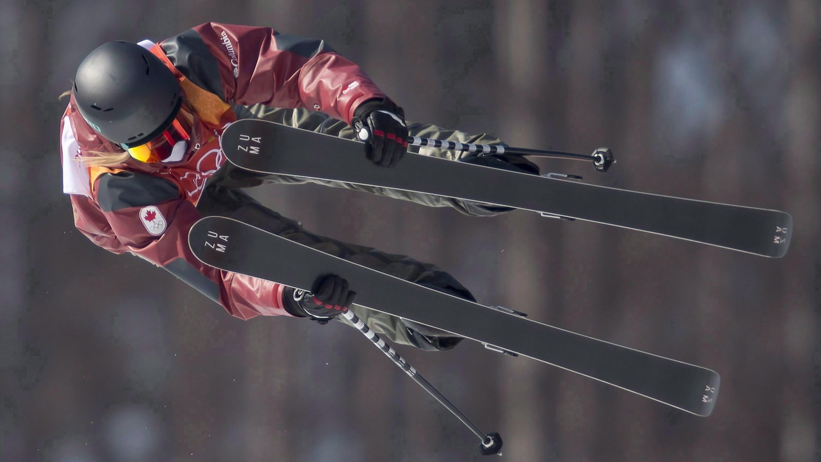 Elle fait une prise de skis dans les airs.