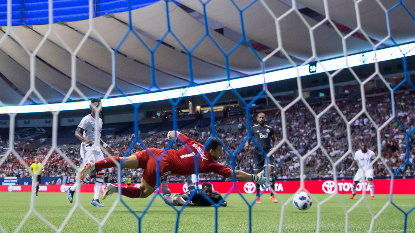 Doneil Henry (en bas, au centre), des Whitecaps de Vancouver, regarde le ballon traverser la ligne des buts derrière son propre gardien, Stefan Marinovic, dans le match aller de la finale du Championnat canadien contre le Toronto FC.