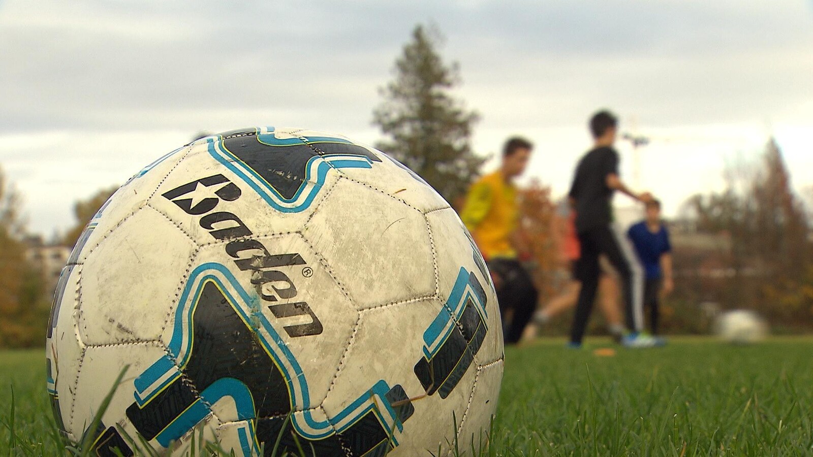Des enfants jouent derrière un ballon de soccer.