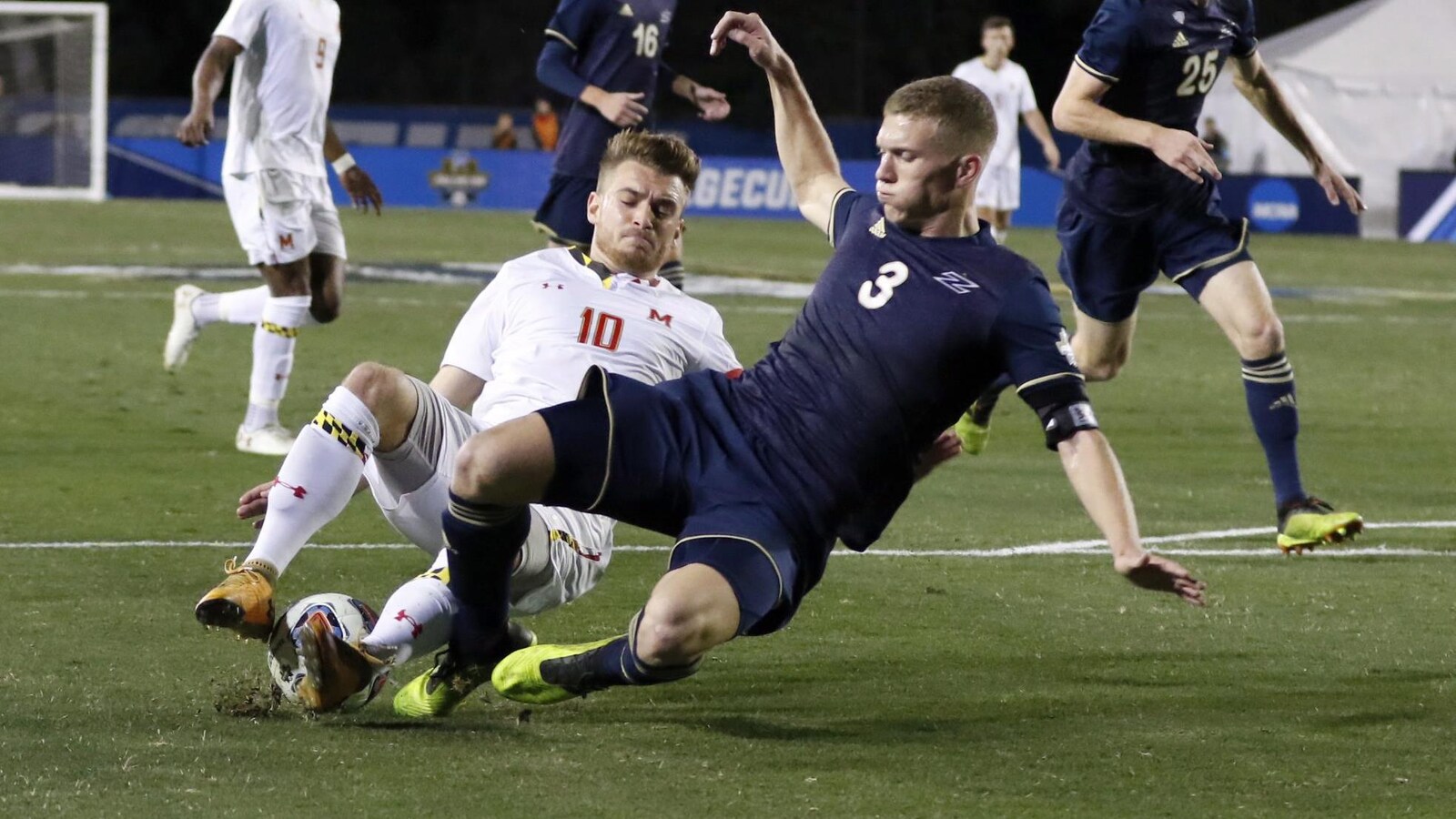 Amar Sejdic (à gauche), de l'Université du Maryland, et Cario Ritaccio, d'Akron), se jettent au sol pour mettre le pied sur le ballon.