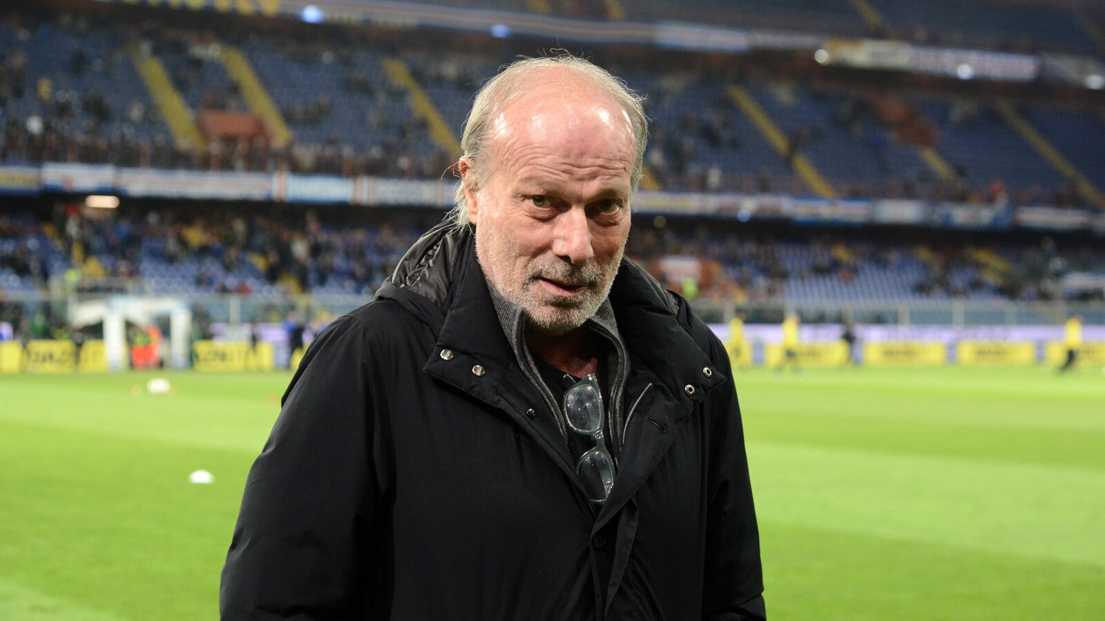 Il est sur le bord d'un terrain de soccer.