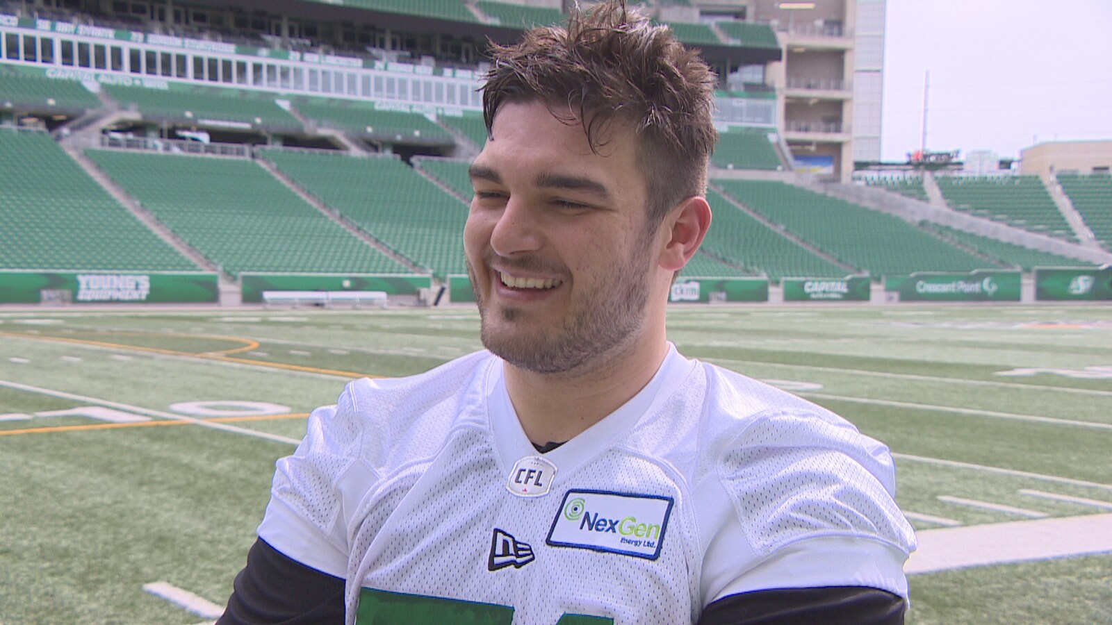 Vincent Roy tout sourire en entrevue à Radio-Canada aux abords d'un terrain de football.