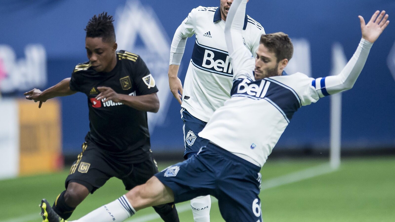 Un joueur des Whitecaps se bat pour la possession du ballon avec son adversaire du FC Los Angeles. Il glisse sa jambe vers le ballon.