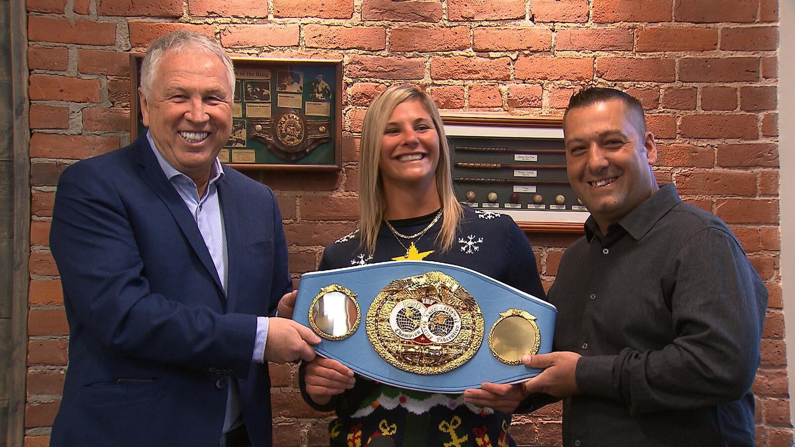 Elle tient sa ceinture entre les deux hommes.