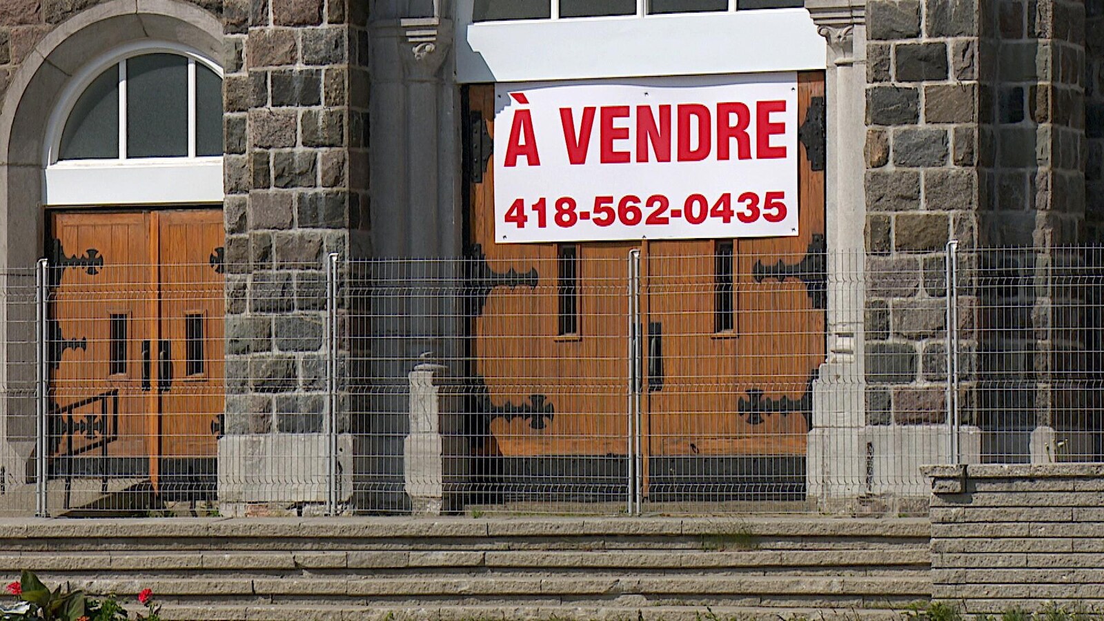 Portes de l'église avec une pancarte À Vendre et un numéro de téléphone.