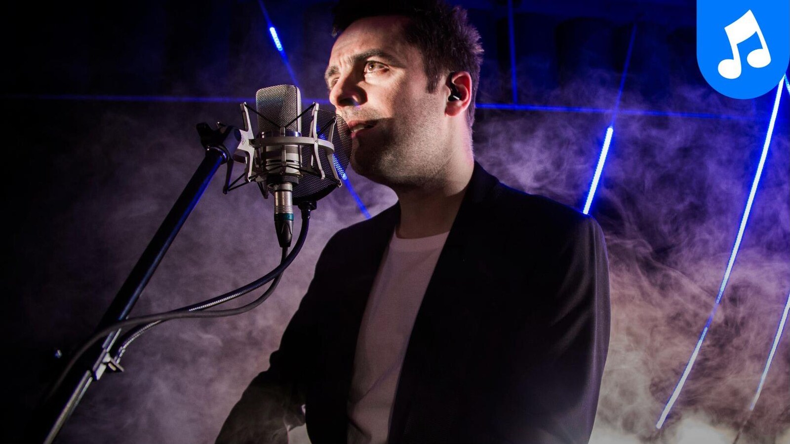 Dumas en prestation solo, chante au micro, une guitare Gibson dans les mains.