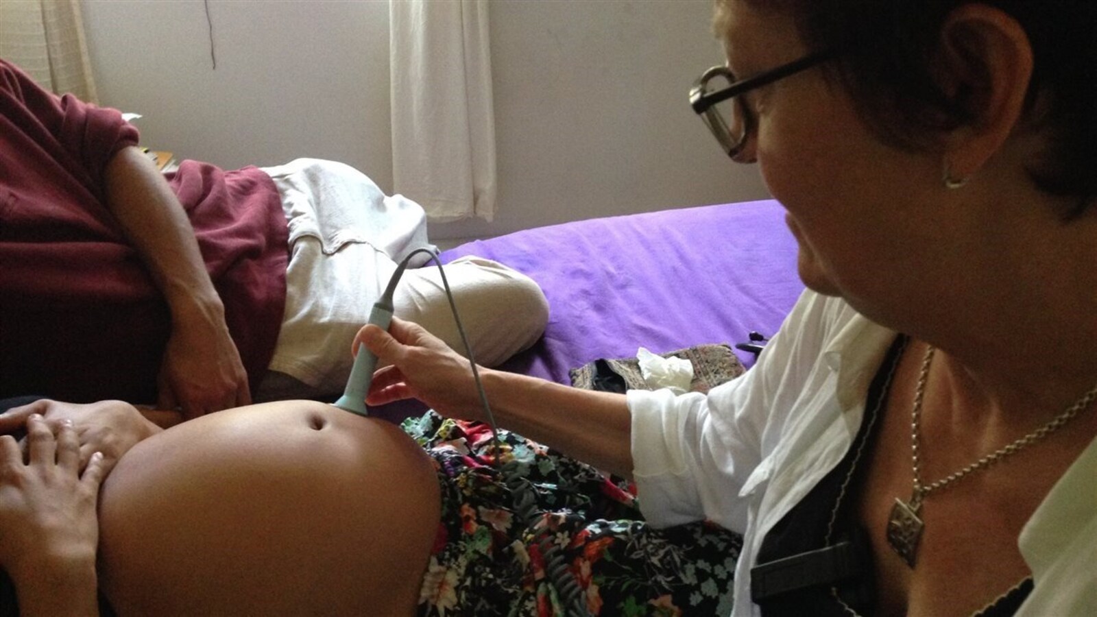 Une sage-femme ausculte un cœur fœtal à l’aide d’un appareil à ultrasons.