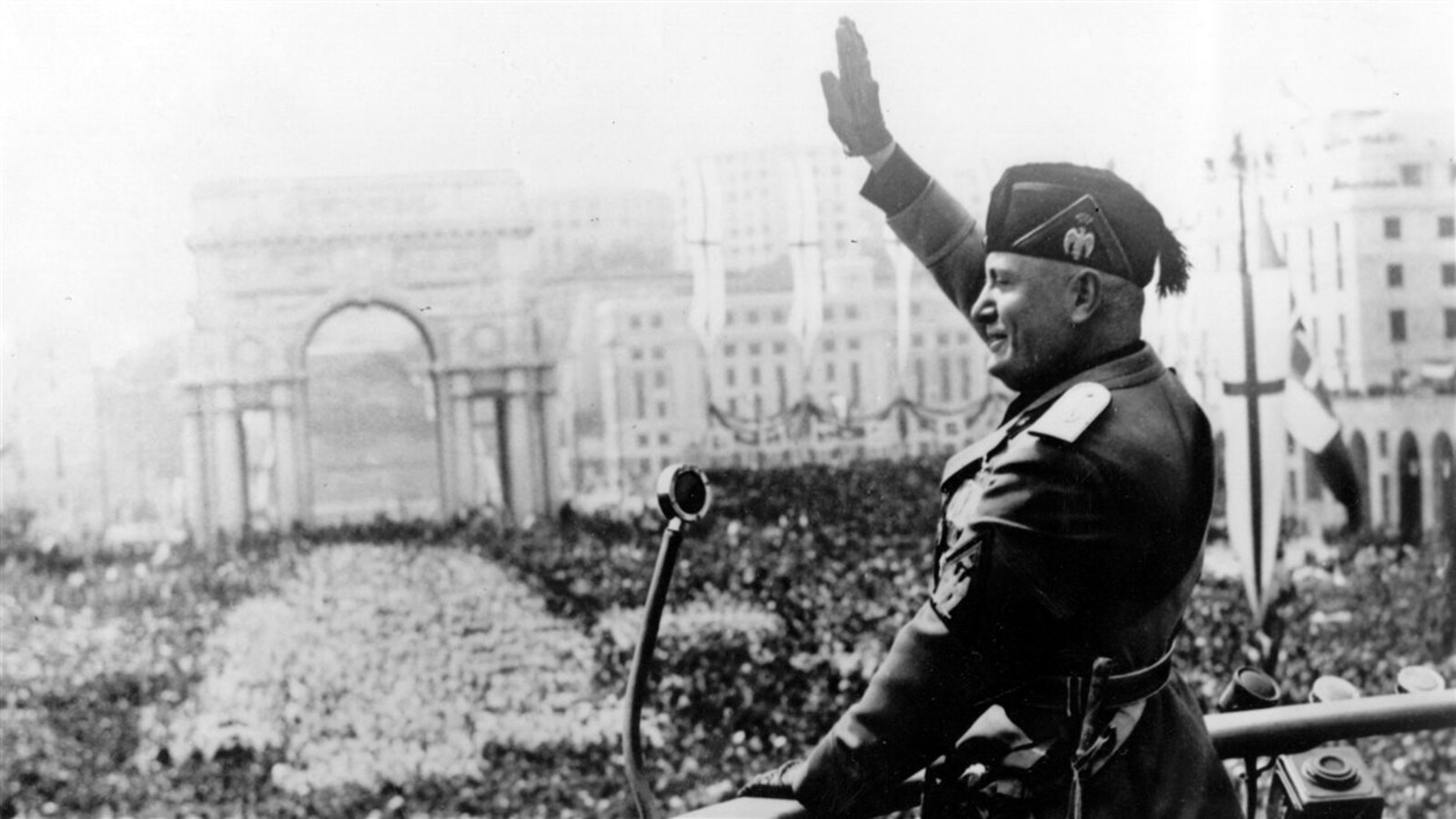 Le dictateur italien Benito Mussolini donne un discours du haut d'un balcon devant une très grande foule.