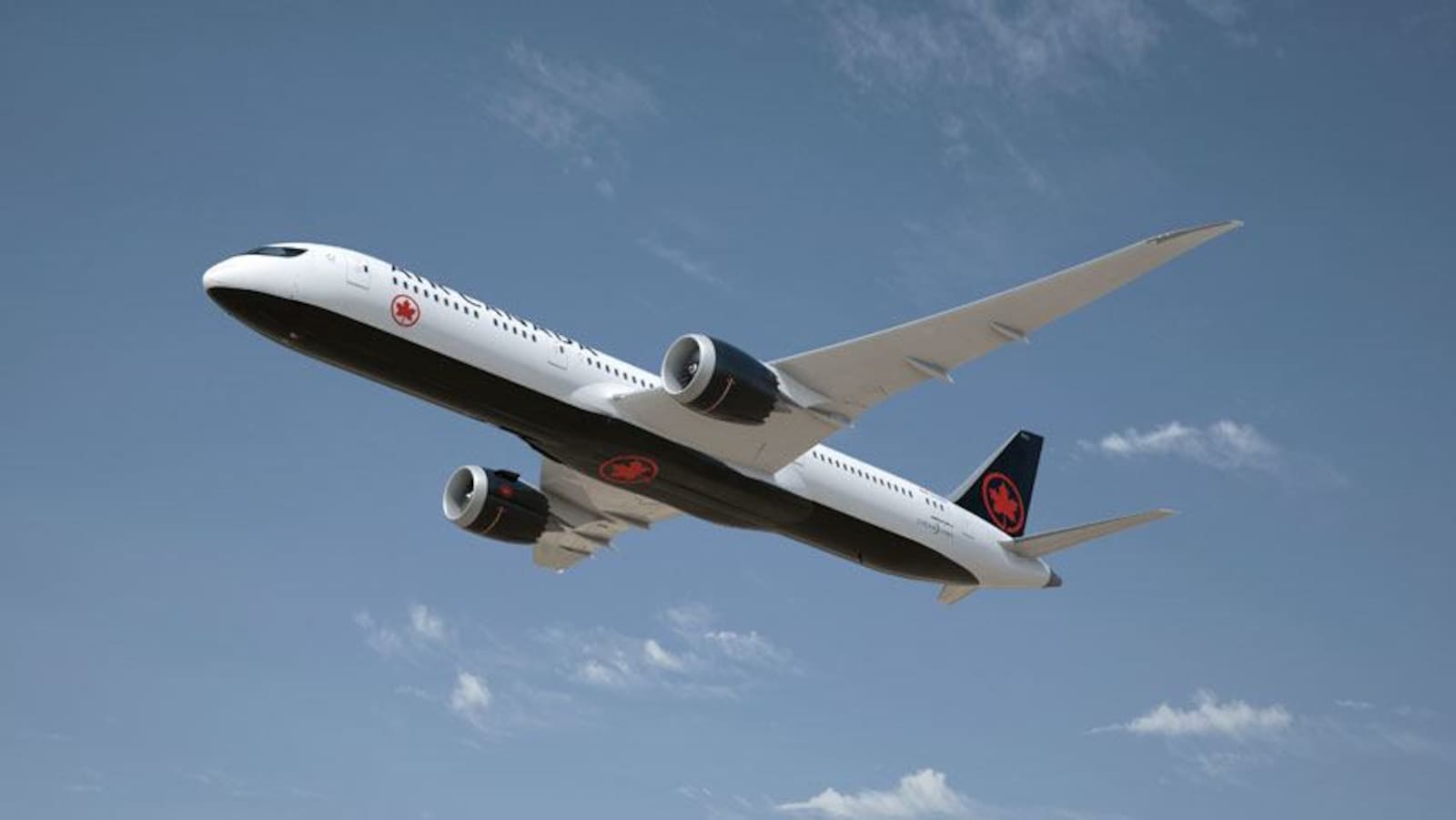 Un avion peint aux couleurs d'Air Canada (noir et rouge) en plein vol.