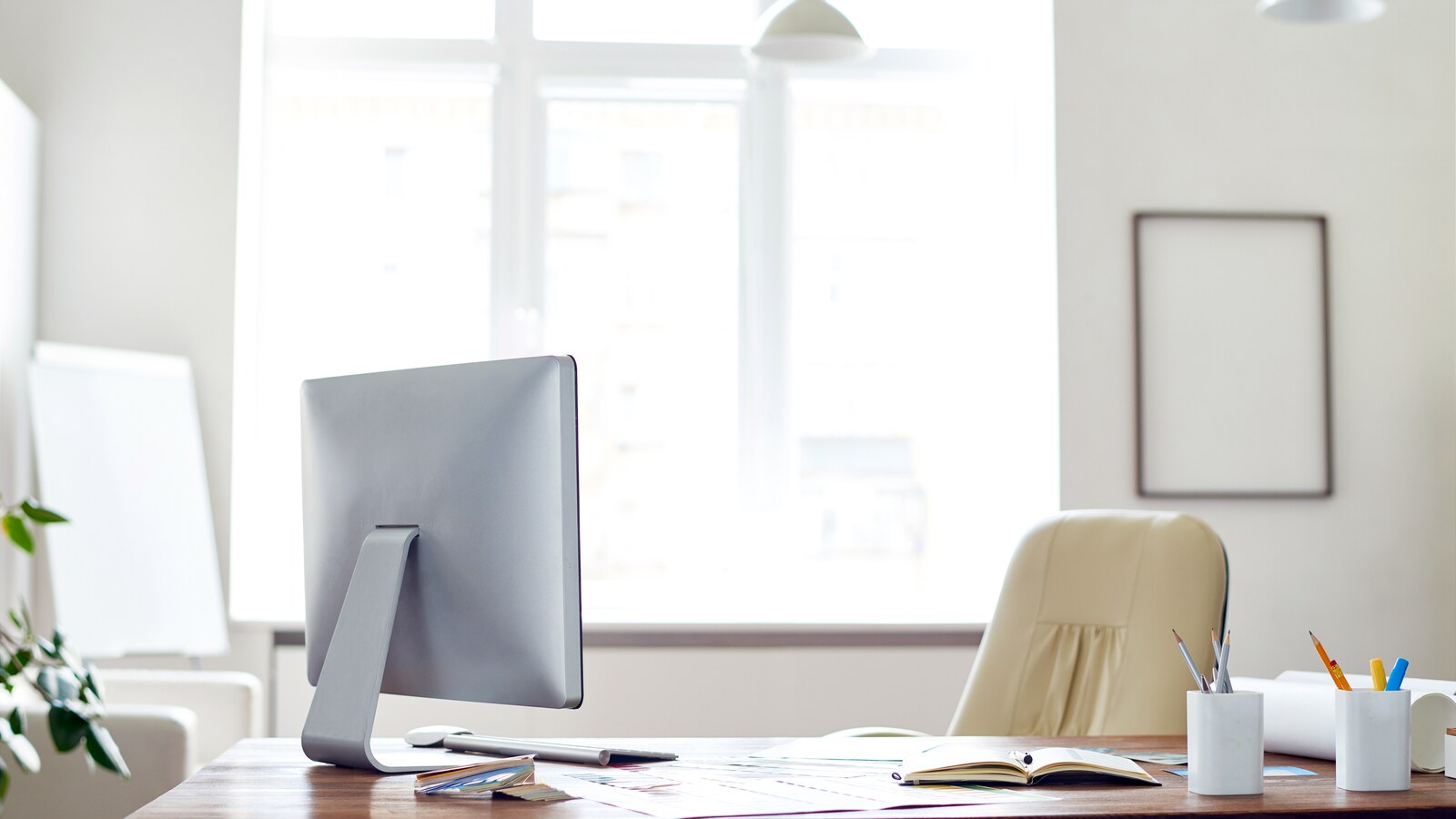 Un bureau avec un ordinateur, du papier et des fournitures et une chaise.