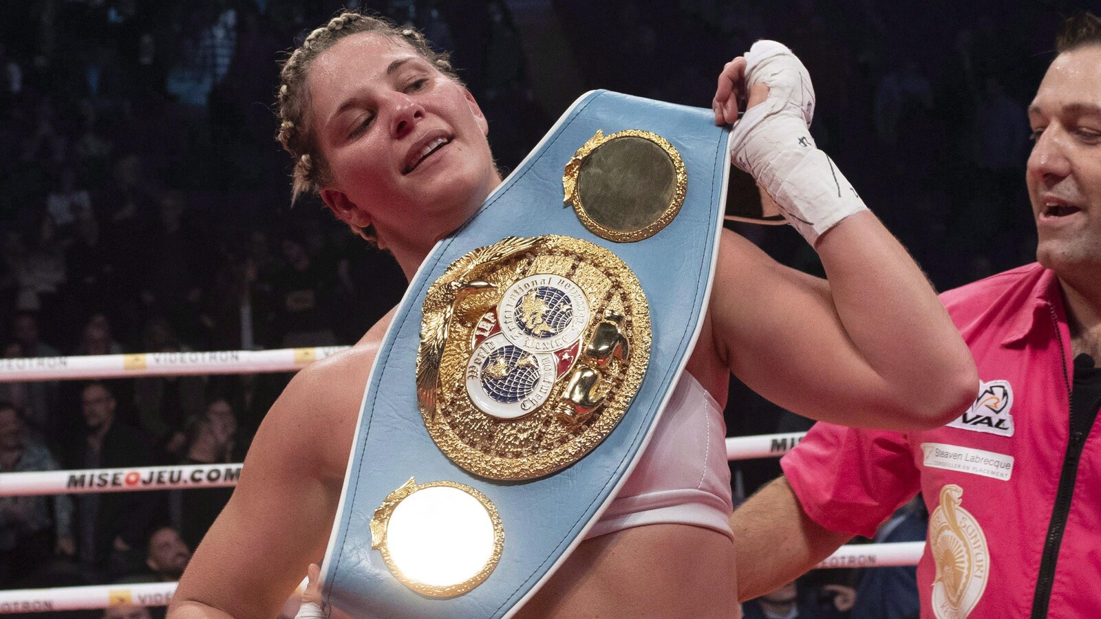 Elle est dans un ring et tient une grande ceinture ornementée d'écussons et de dorures.