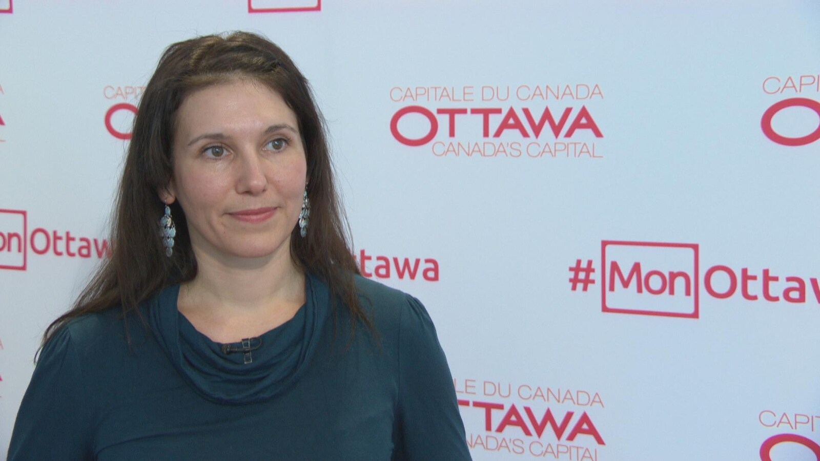 Catherine Callary en entrevue devant un fond blanc portant l'inscription « capitale du Canada, Ottawa ».