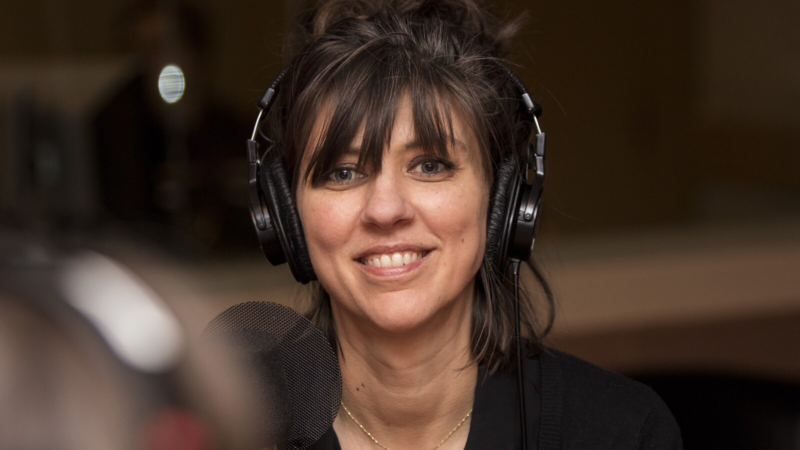 Catherine Ocelot sourit devant un micro dans un studio de radio.