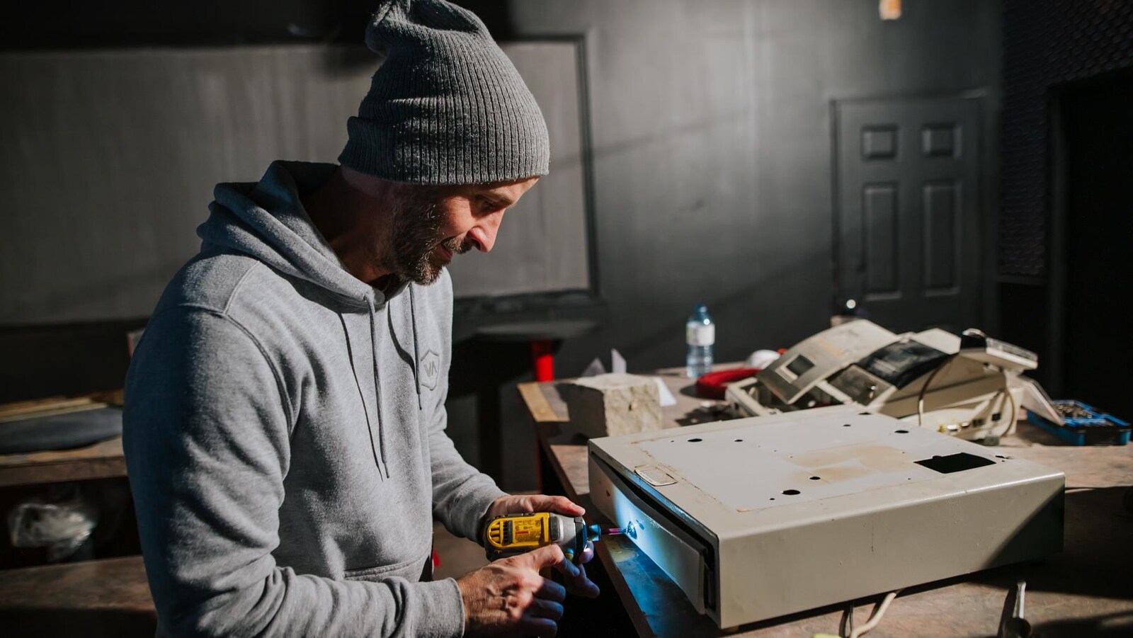 Un homme travaille à la réparation du tiroi- caisse d'un bar.