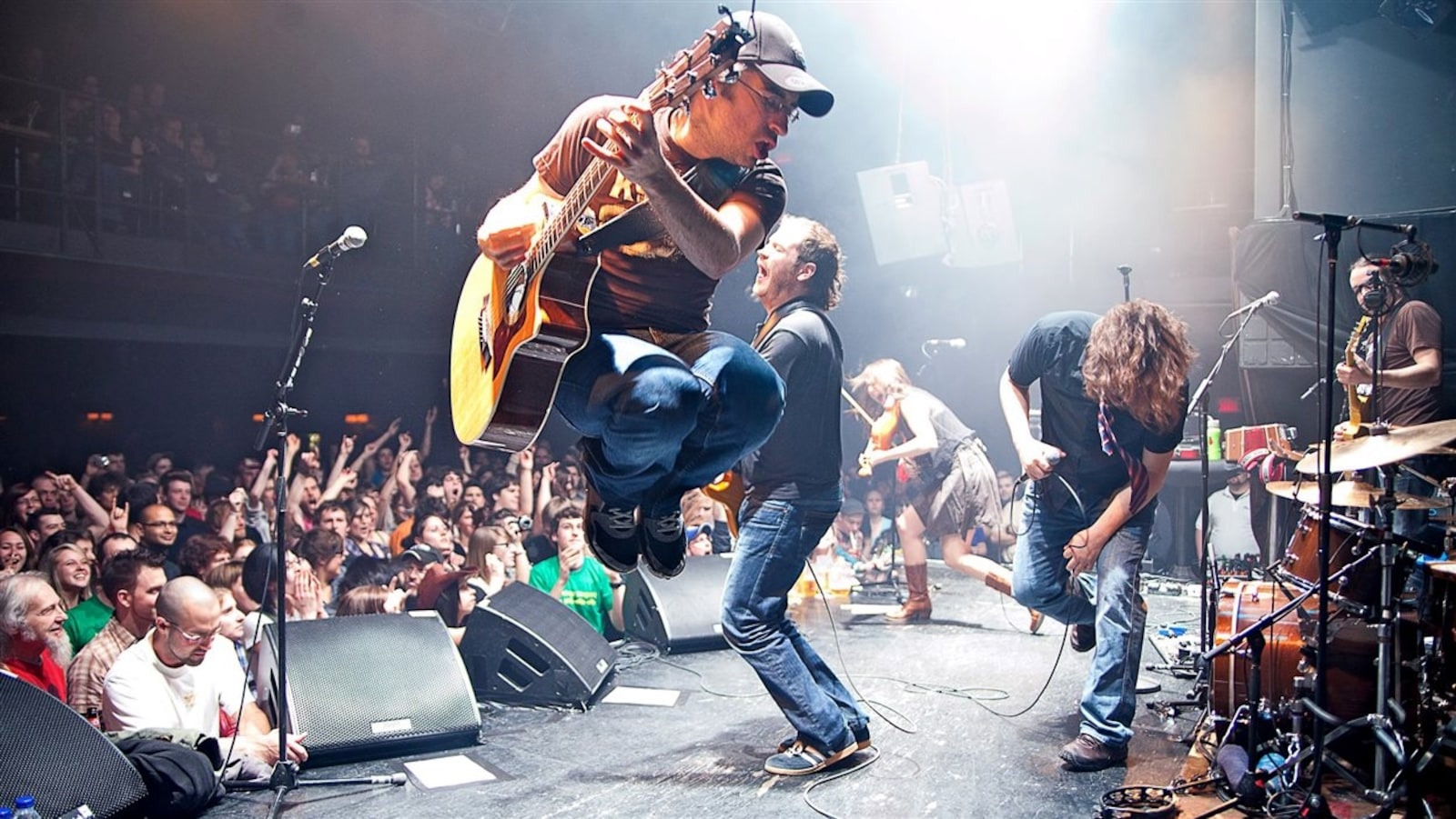 Un guitariste saute dans les airs devant une foule en liesse.