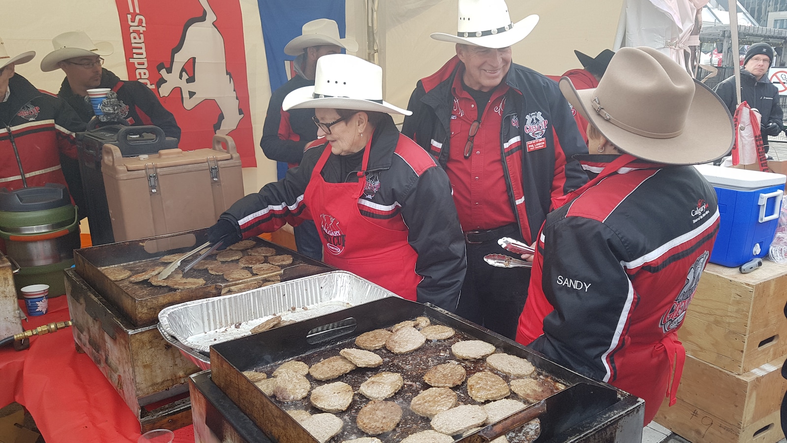 Des gens habillés en cowboys qui font cuire des saucisses et des crêpes