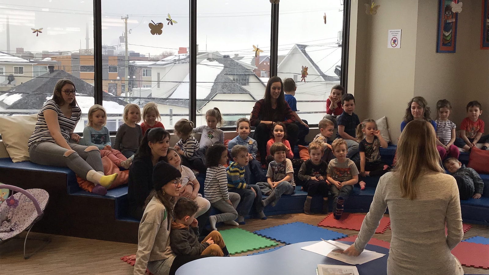 Des enfants sont réunis en cercle dans les locaux d'une bibliothèque.
