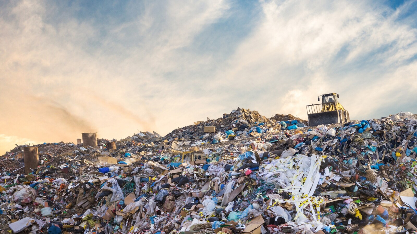 Un véhicule repousse des piles de déchets dans un dépotoir.
