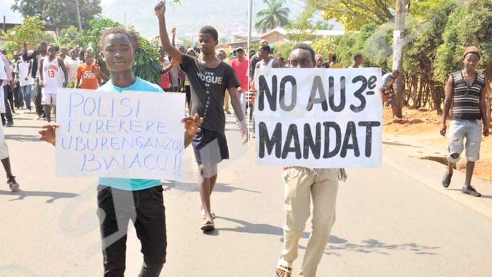 Un jeune manifestant tient une pancarte sur la quelle il est écrit : No au 3e mandat.