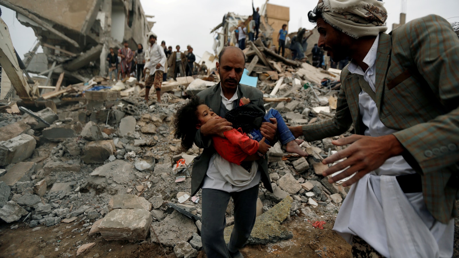 Un homme porte une fillette blessée, sauvée d'une attaque aérienne dirigée par l'Arabie saoudite à Sanaa, au Yémen