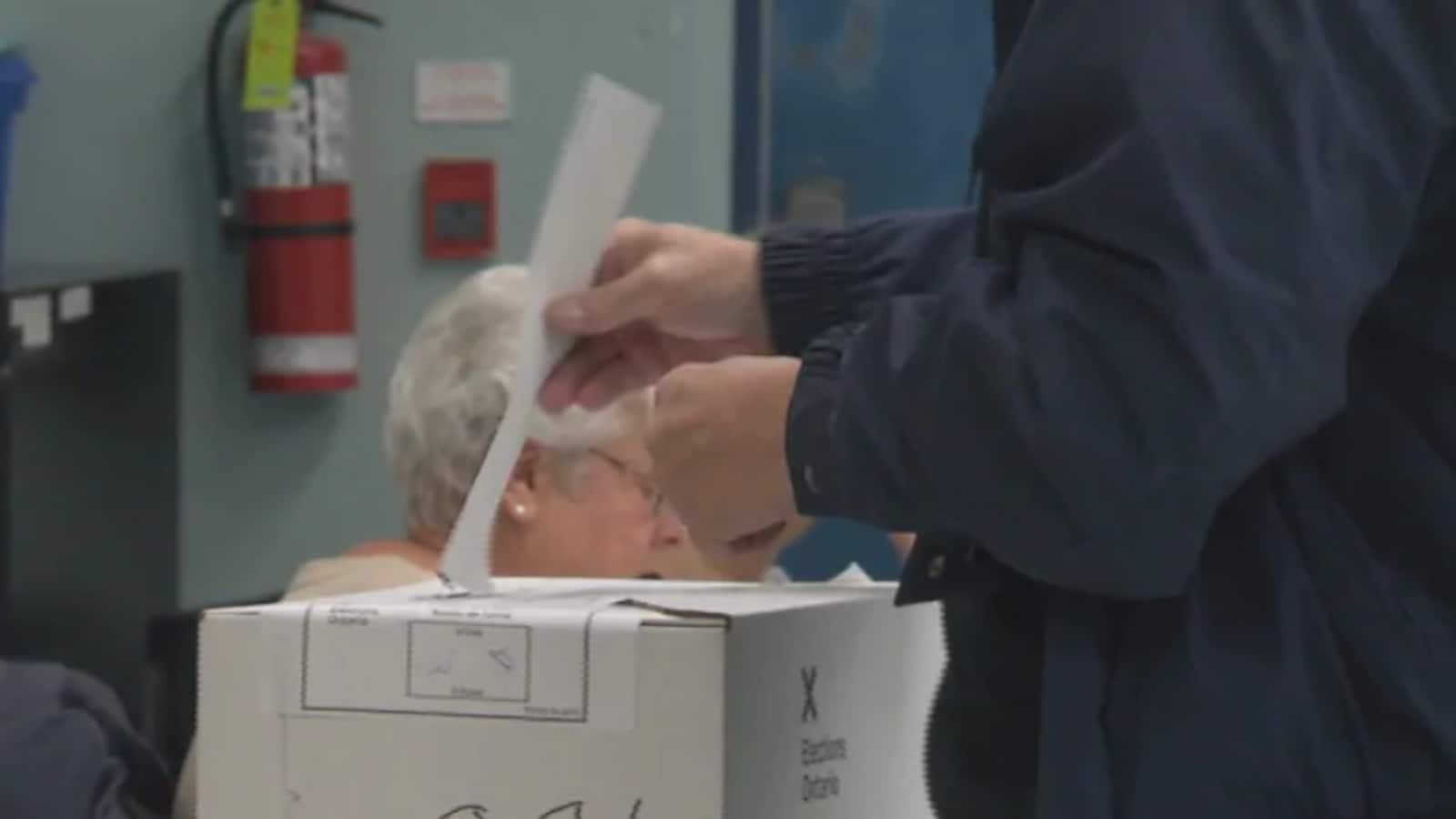 Un homme glisse son bulletin de vote dans une urne.