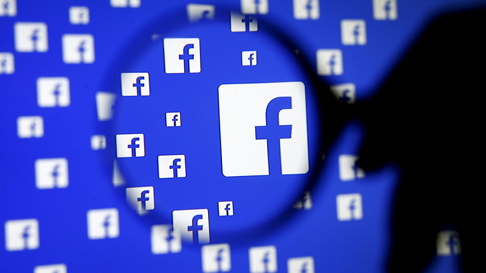 Une loupe devant un logo Facebook.