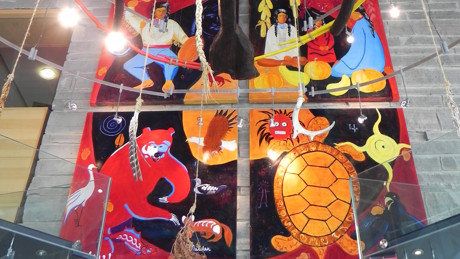 Tableau peint sur quatre panneaux représentant une famille des Premières Nations et des animaux dont un ours et une torture.