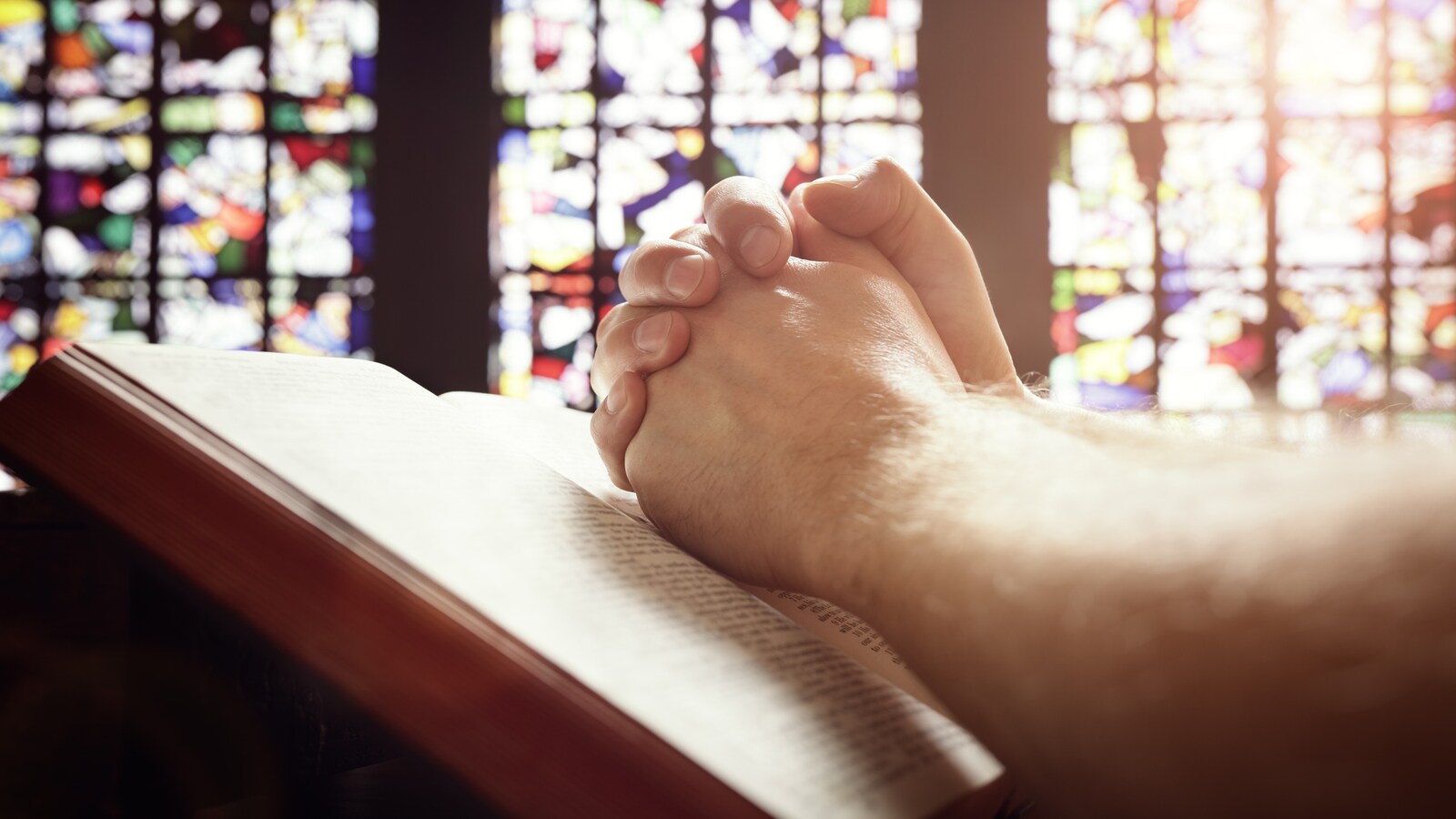 Un croyant prie les mains sur la bible.