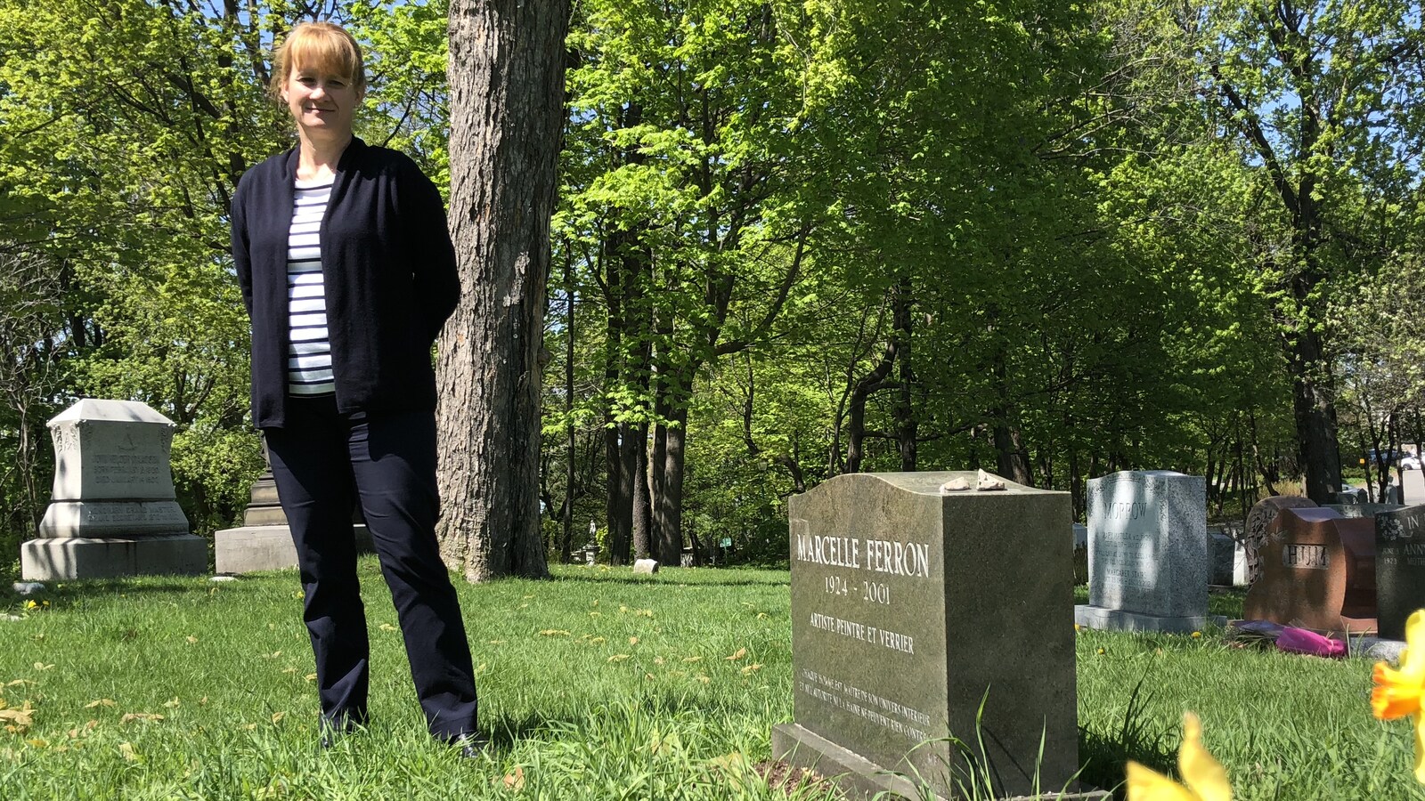 La directrice des programmes du patrimoine au Cimetière Mont-Royal de Montréal, Myriam Cloutier, devant la pierre tombale de la peintre Marcelle Ferron