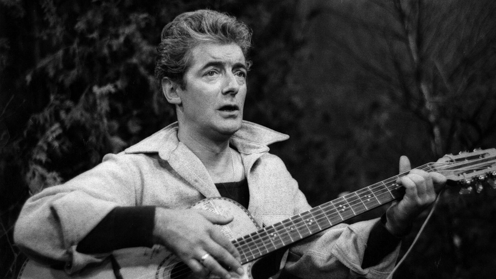 Le chanteur Félix Leclerc chante avec sa guitare.