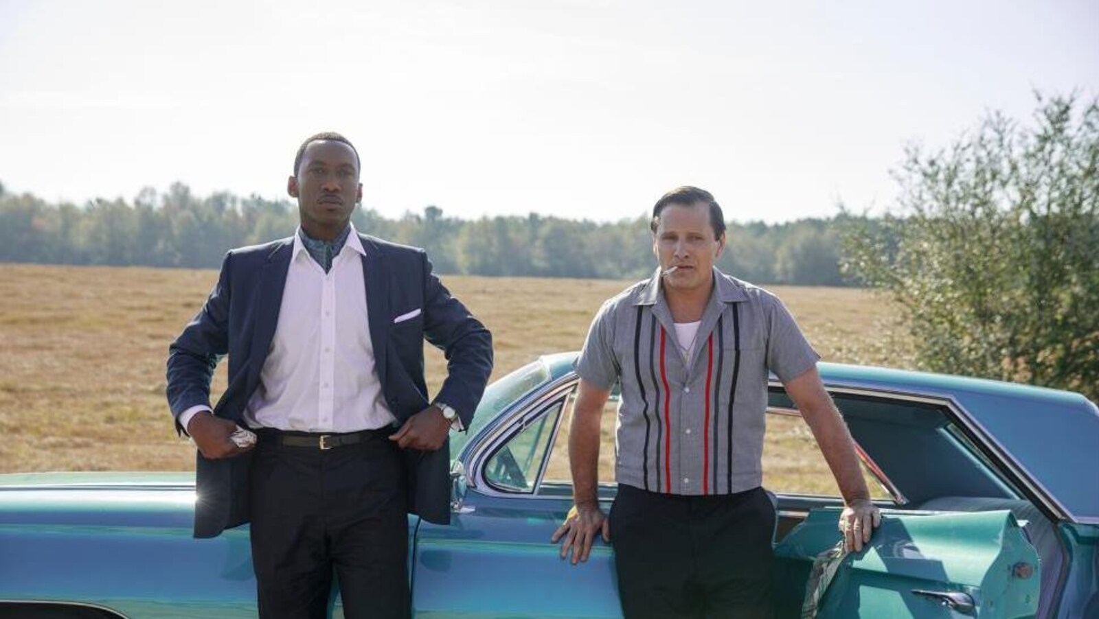Les deux hommes sont devant une voiture bleue.