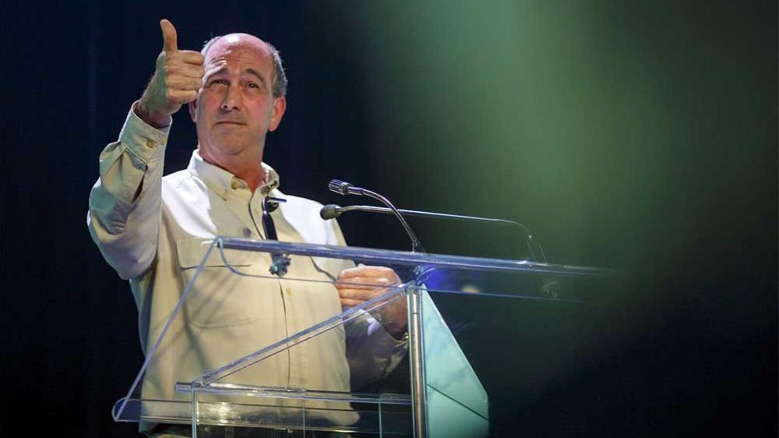 Un homme se tient devant un podium sur une scène. Il donne une conférence.