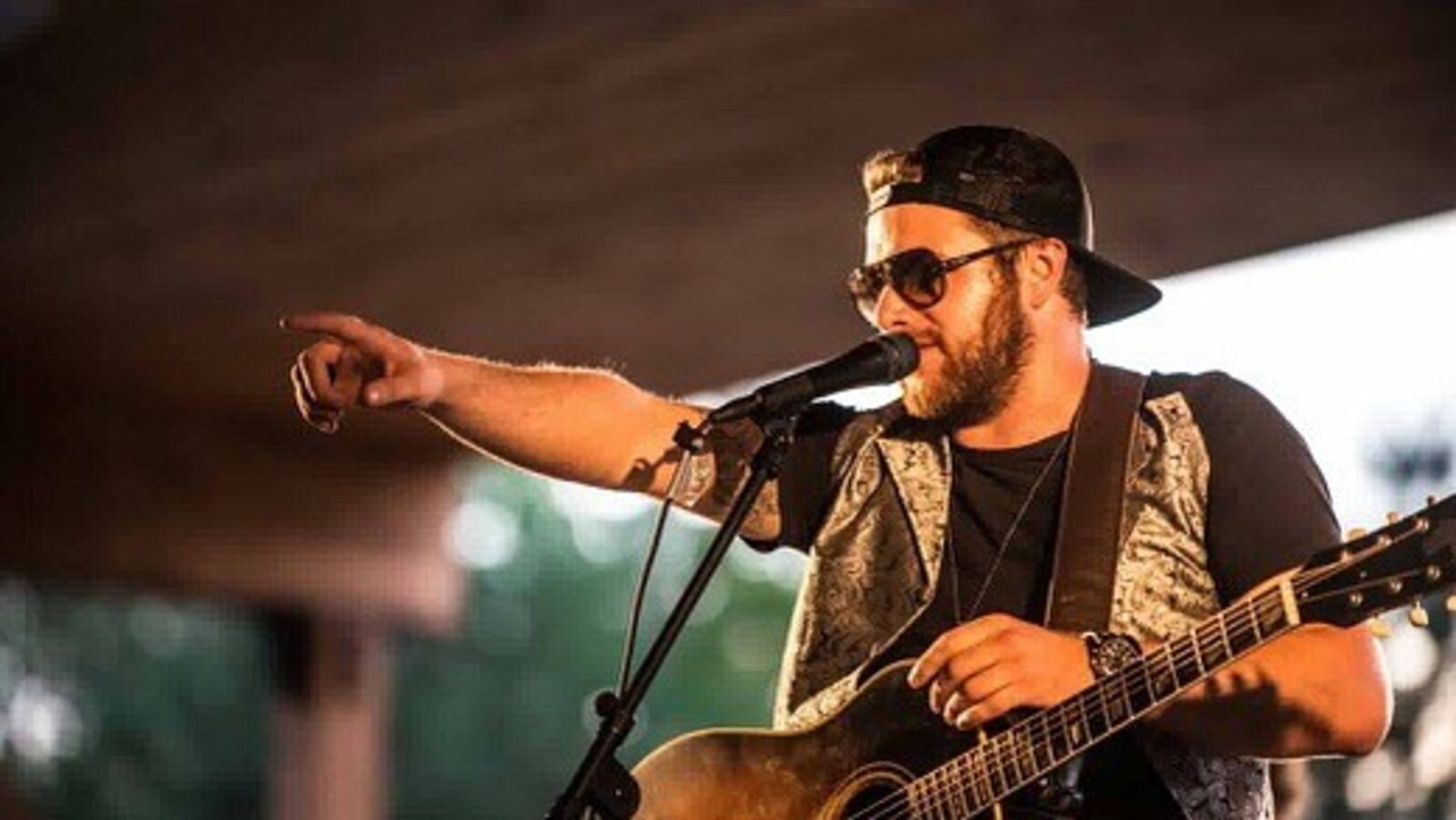 Mathieu Langevin chante, sa guitare au cou, et pointe vers la foule.
