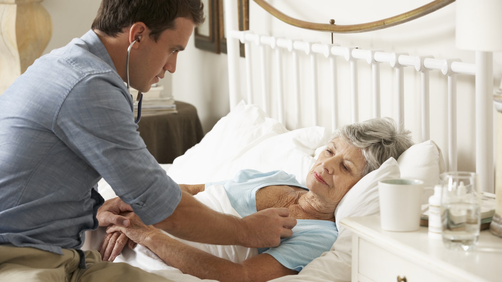 Un médecin pratique des soins à domicile auprès d'une vielle femme.