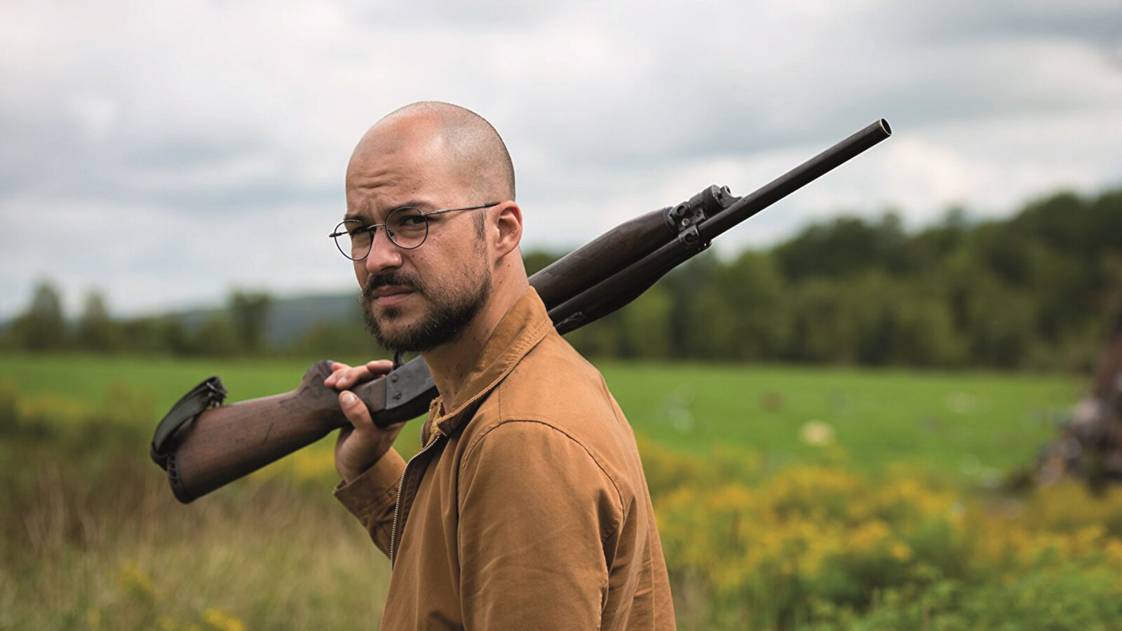 Dans un champ, Marc-André Grondin tient un fusil sur l'épaule