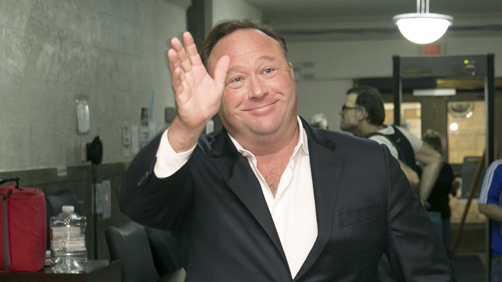 Une photo montrant Alex Jones, souriant, en train de saluer quelqu'un.