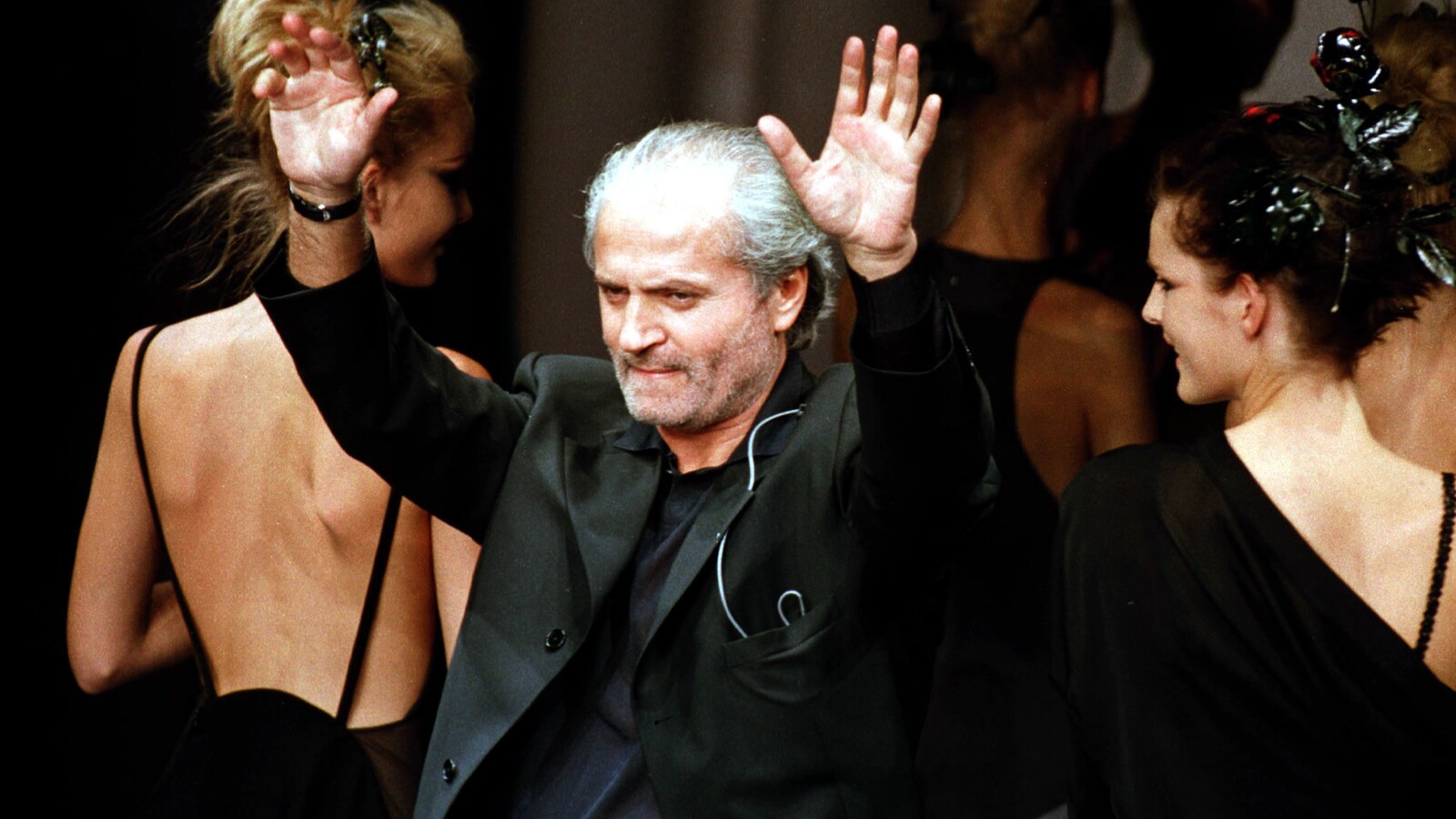 Gianni Versace salue la foule lors d'un défilé de mode, en 1996.