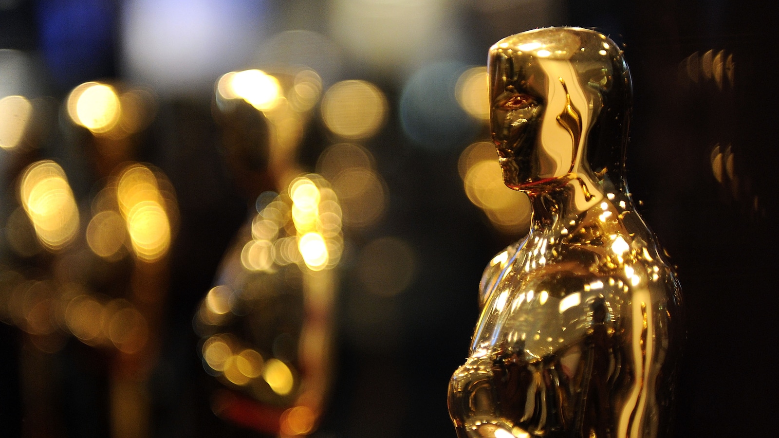 Des statuettes dorées de l'Académie des Oscars brillent sous l'éclairage.