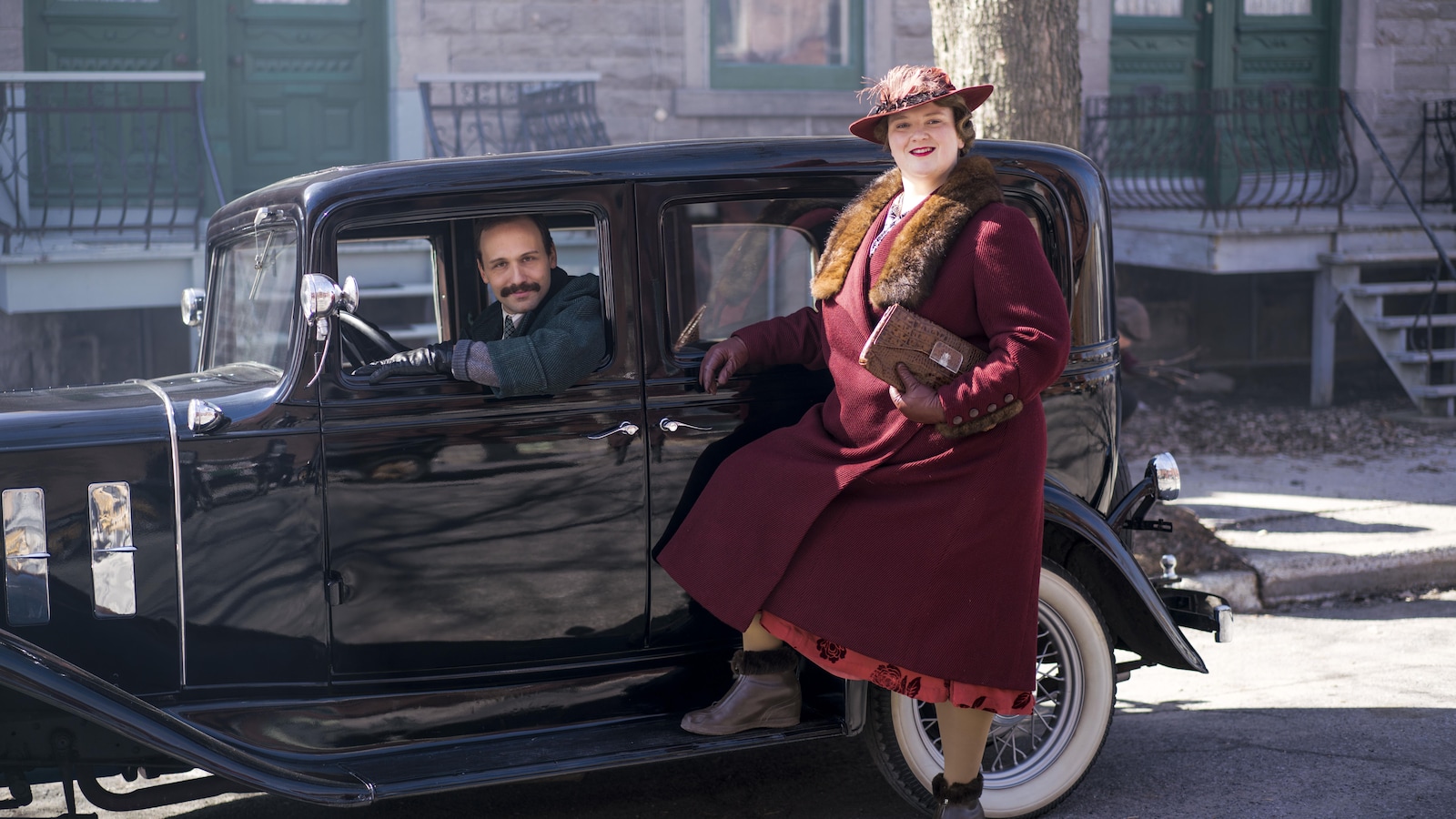 Émile Proulx-Cloutier est au volant d'une voiture d'époque stationnée et Debbie Lynch-White est debout à côté dans cette image tirée du film <i>La Bolduc</i>, de François Bouvier.
