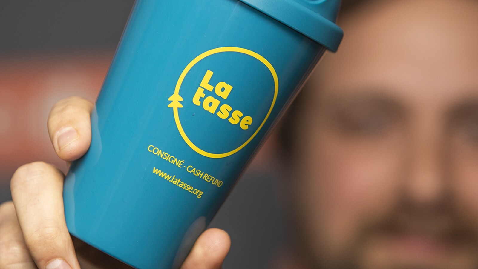 Un homme tient une tasse bleue en plastique.