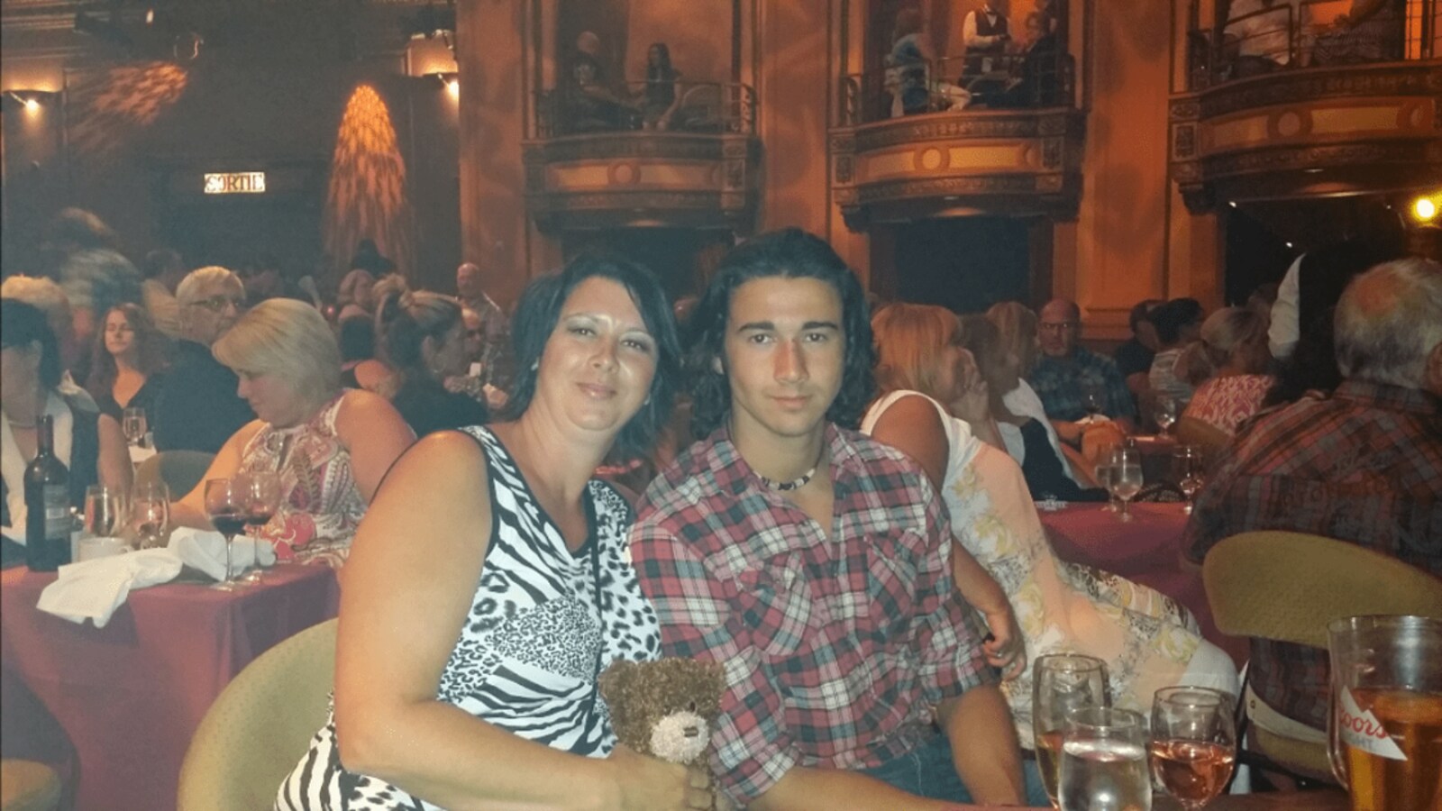 Photographie de famille de Wanny Pelletier et de sa mère assis à une table au milieu d'une salle de spectacle.