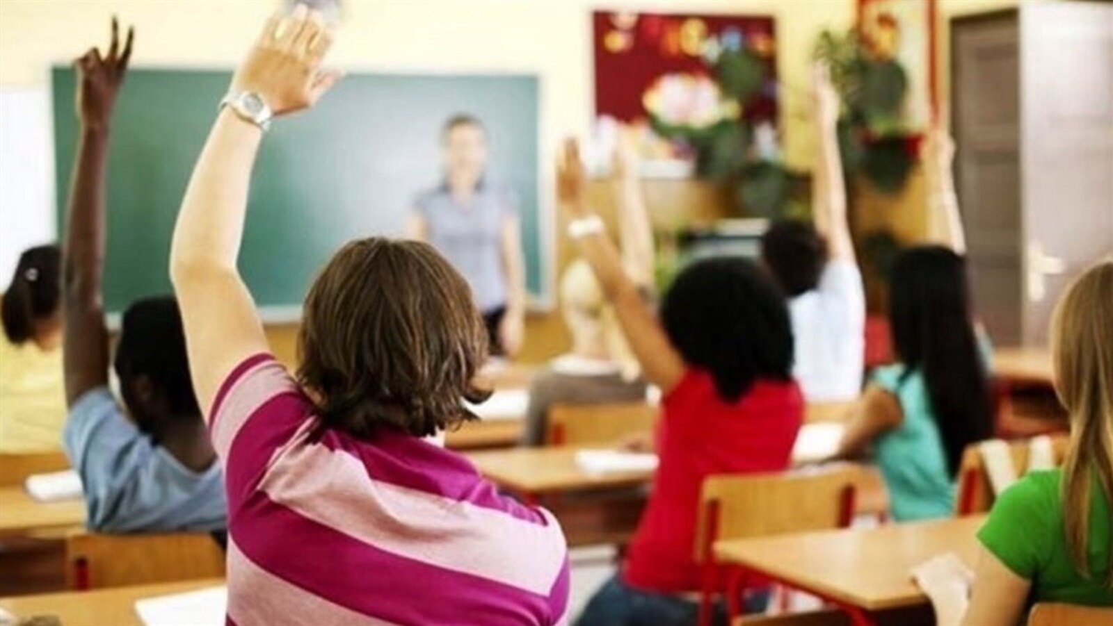 Des élèves lèvent la main dans une salle de classe.