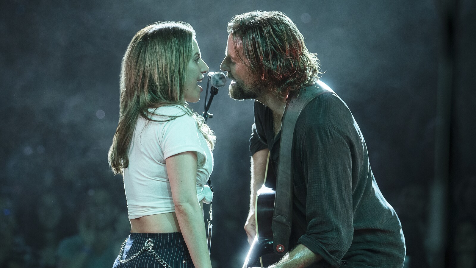 Bradley Cooper dans le rôle de Jack et Lady Gaga dans le rôle d'Ally, chantent tous deux sur scène devant un public enjoué dans le film « A Star Is Born ».